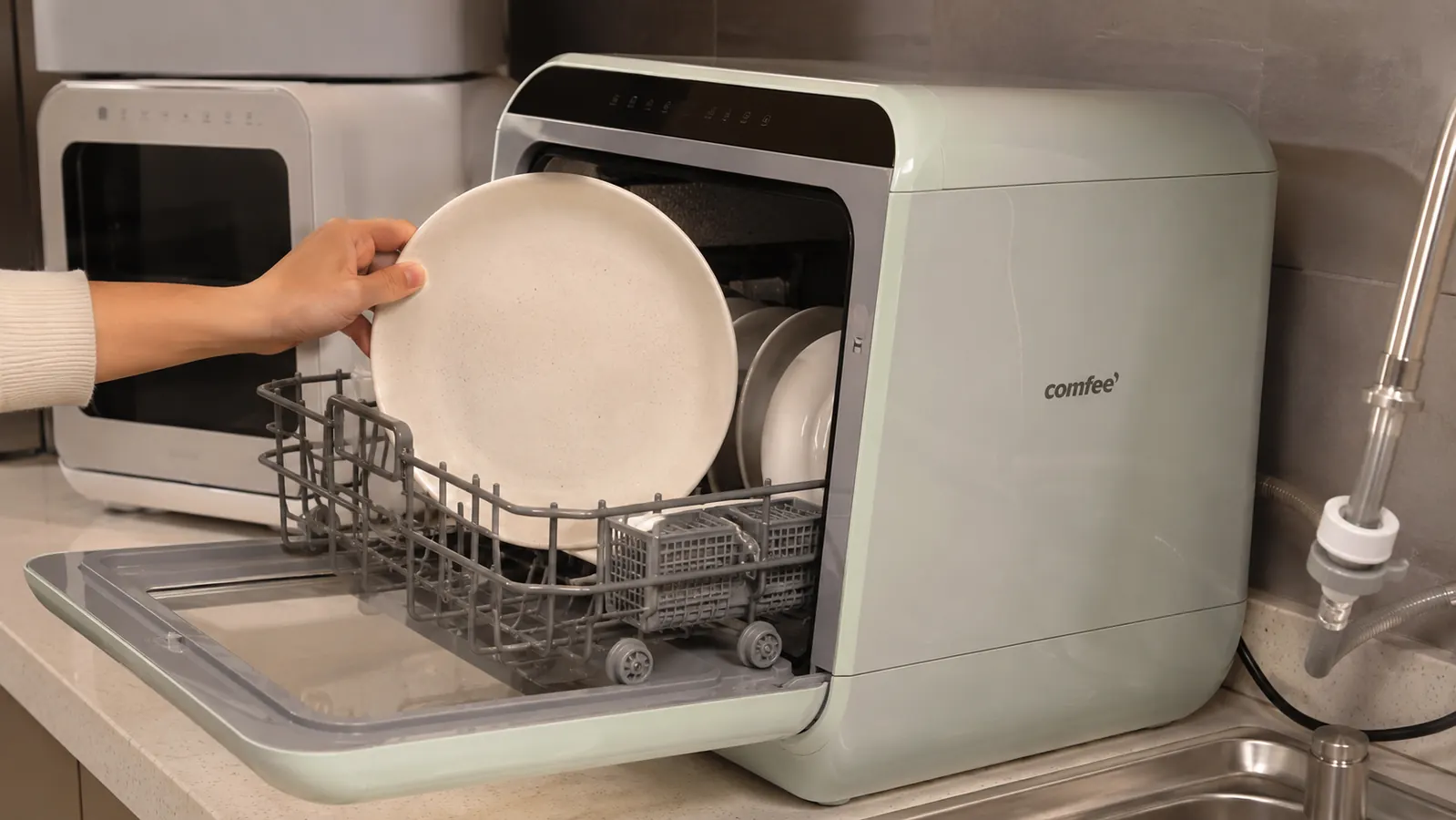 Hand loading dishes into the COMFEE' countertop dishwasher rack during a side-by-side test