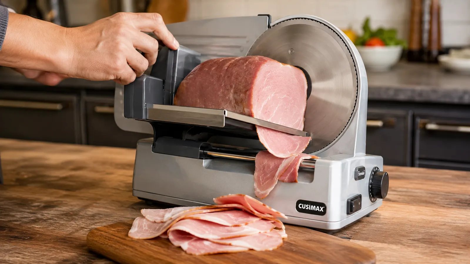 Hand guiding a block of ham through the CUSIMAX slicer's food carriage toward the stainless blade