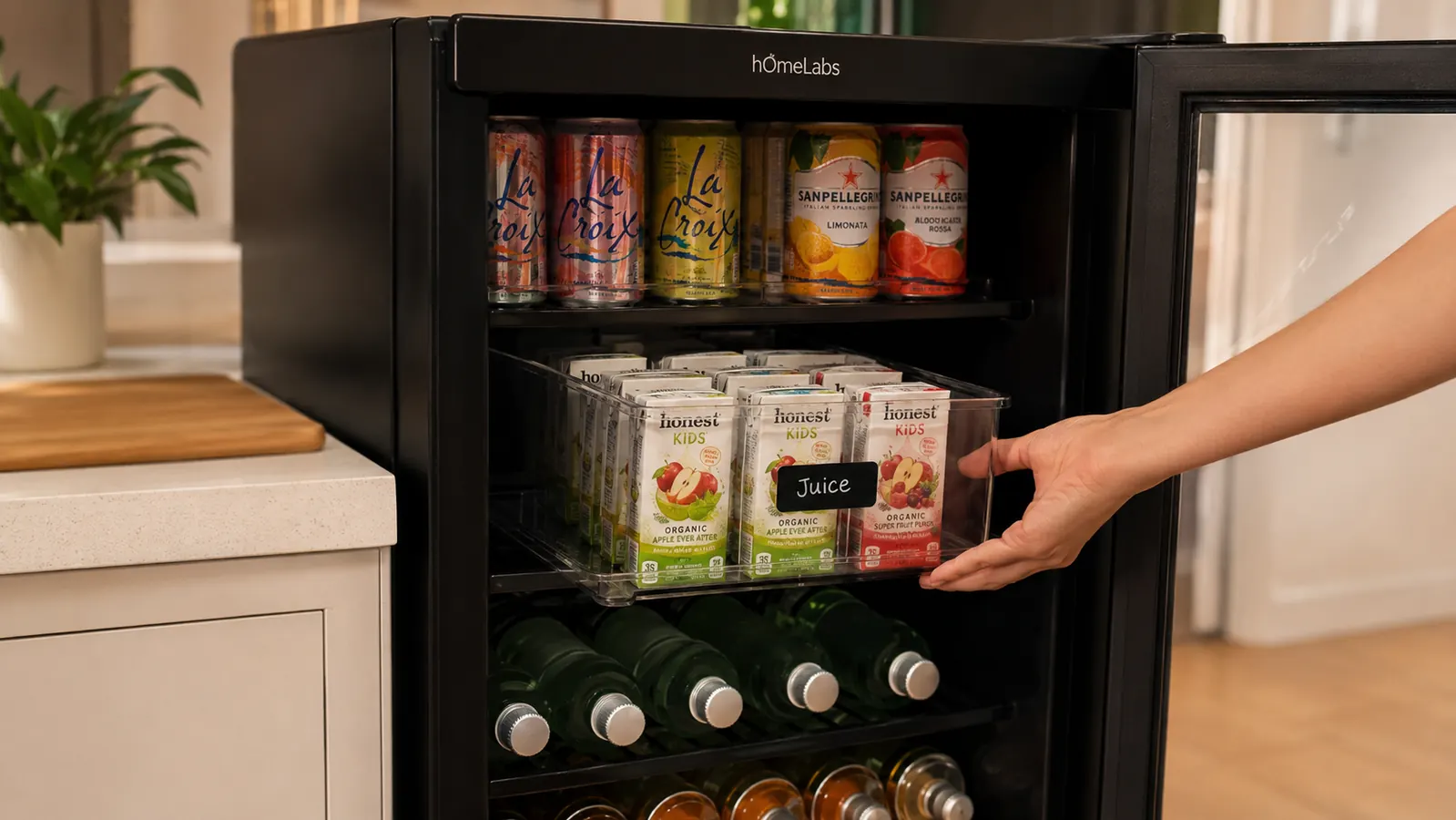 Hand placing a labeled bin of juice boxes onto the middle shelf of a beverage fridge