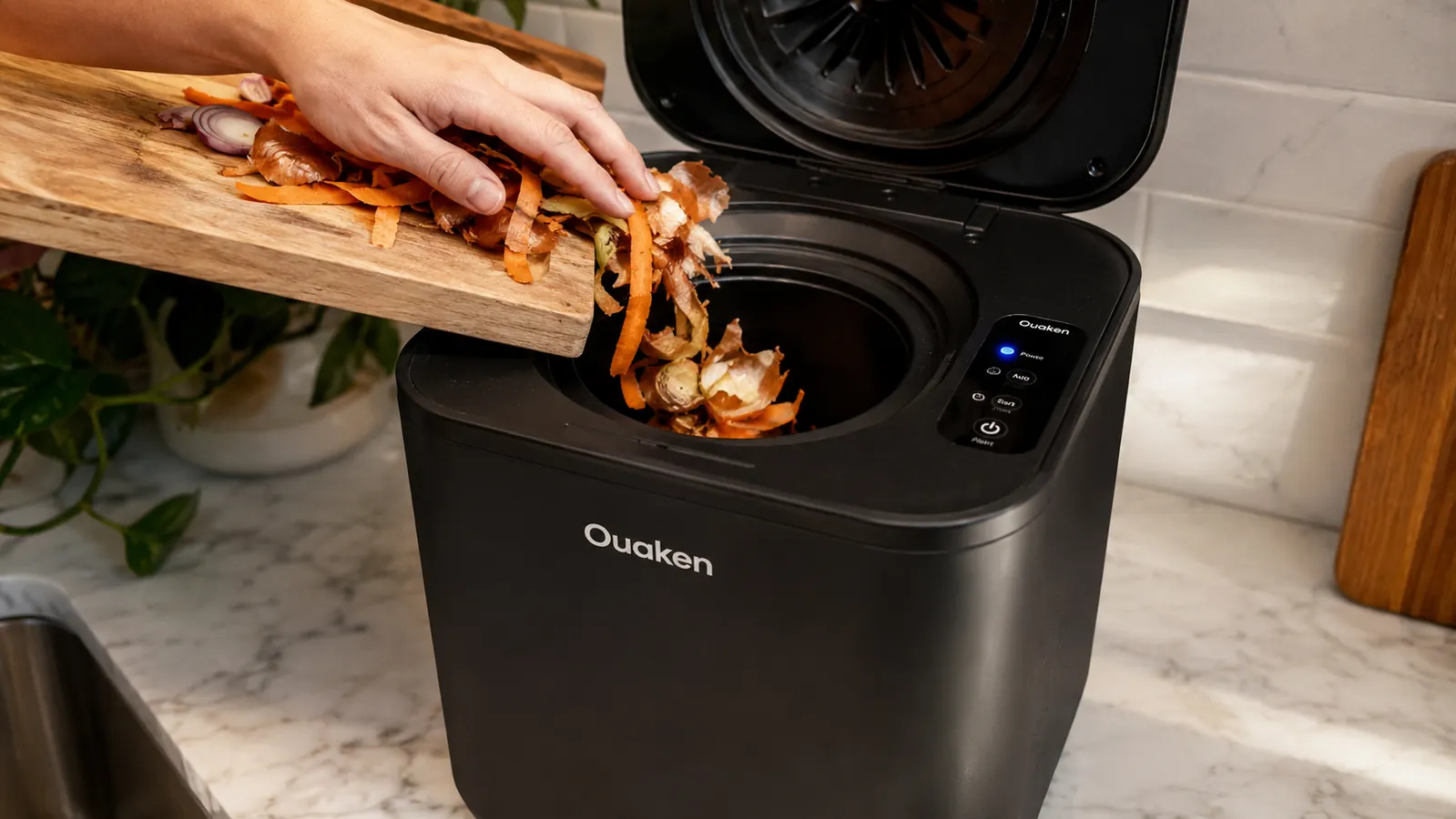 Hand scraping vegetable peels into the open lid of the Ouaken electric composter